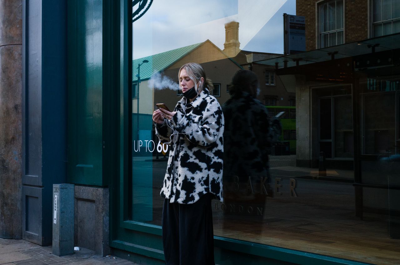 A person smoking in front of a window