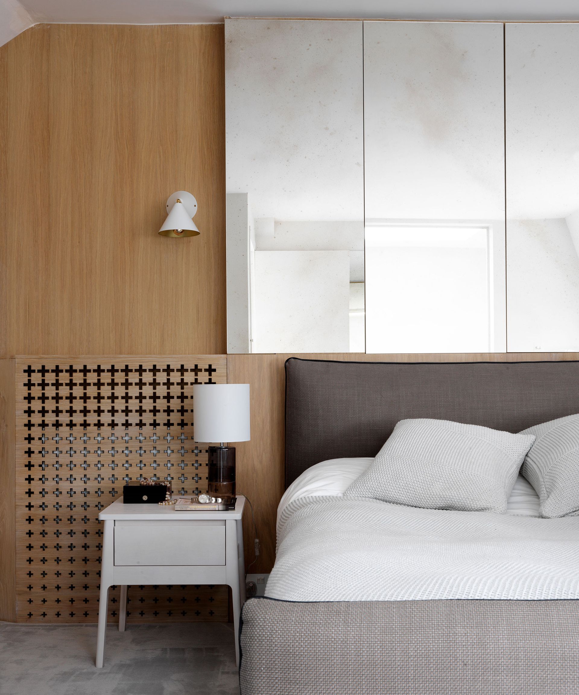 Bed and nightstand with wood wall and mirrors behind