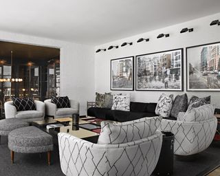 A white games room with black sofa and grey patterned armchairs