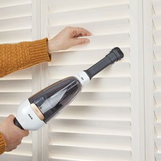 shutters being cleaned with handheld vacuum