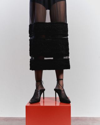 Close up of woman in chanel skirt on red plinth