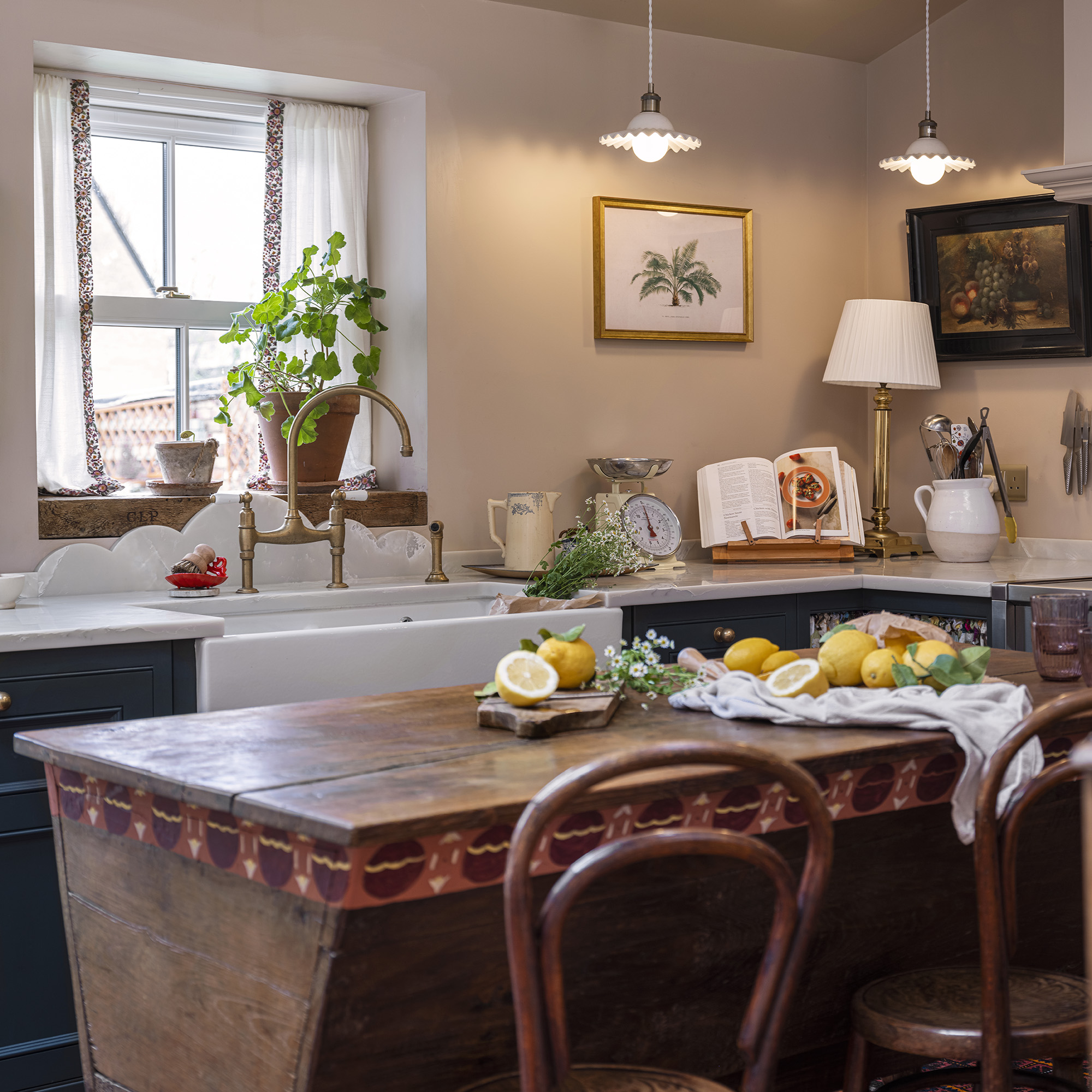 v100-year-old French dough-bin table as an island in kitchen with butlers sink and green cabinetry