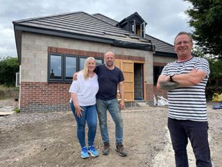 Couple, Jules and Steve stood in front of the completed shell of their bungalow.
