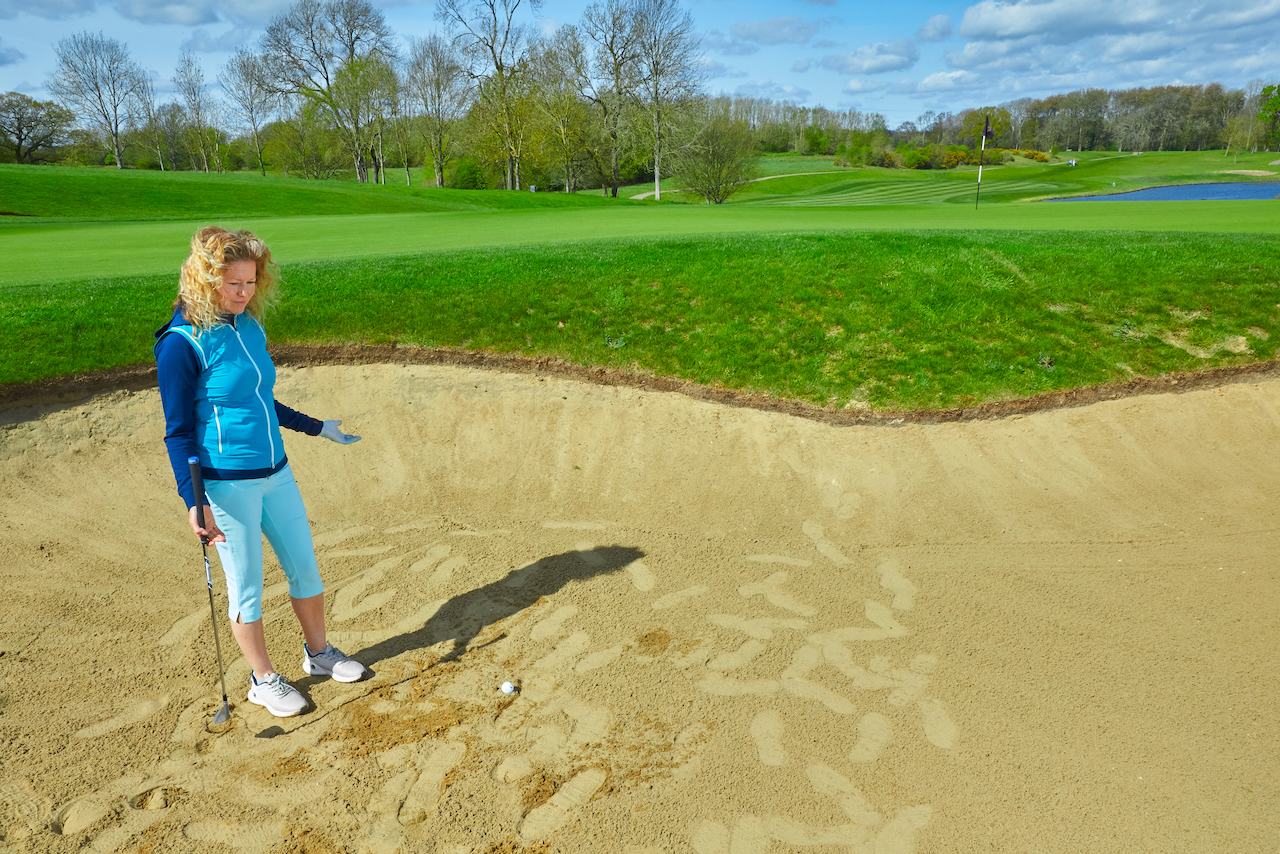 A player standing over a shot in an unraked bunker