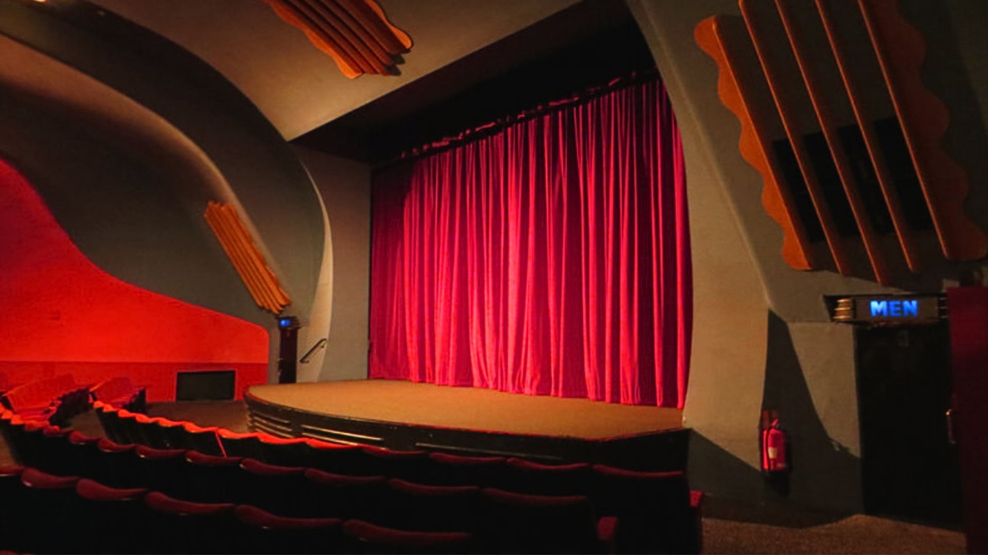 an image of the interior of Hackney's Rio Cinema showing a traditional stage with a heavy red curtain and theatre style seats
