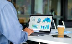 A businessman looks at financial reports on his laptop. 