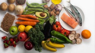 an array of fruits, vegetables, legumes and fish (fillet and whole) on a white background