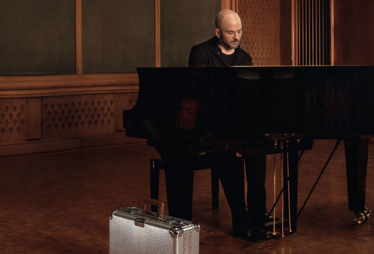 Nils Frahm at the piano with a Rimowa Hammerschlag case beside him