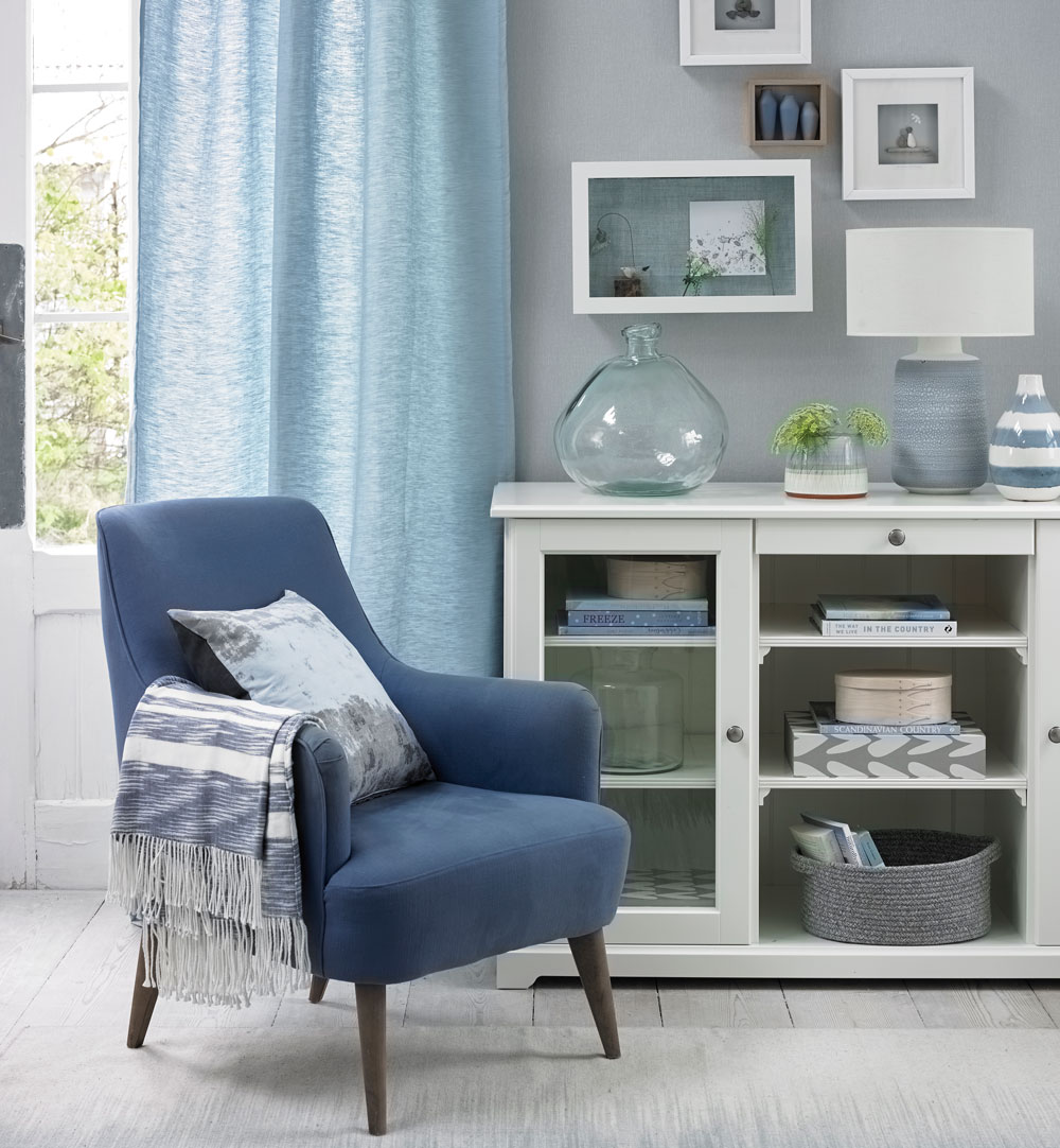 blue living room with pale blue walls and royal blue armchair beside white sideboard