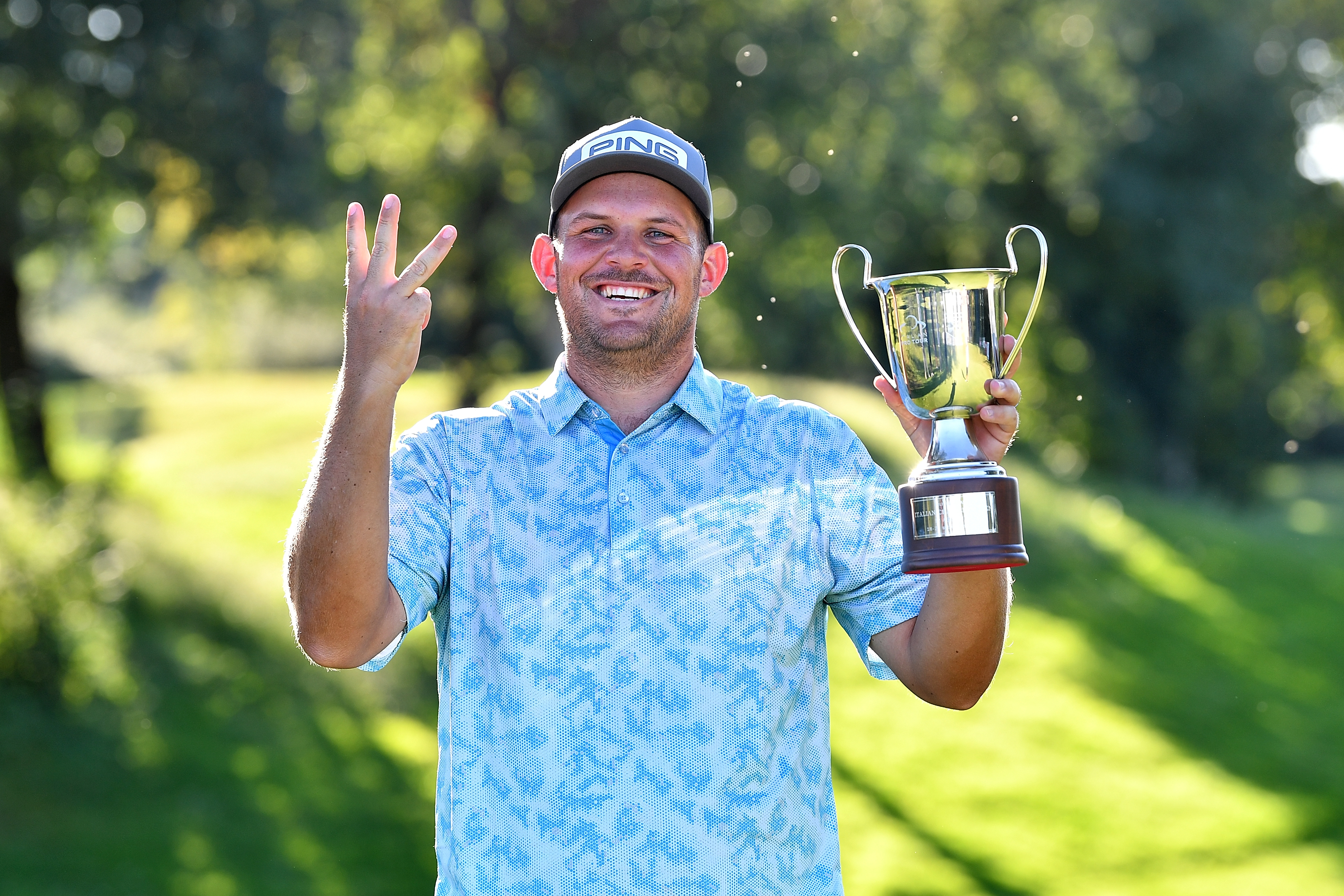 JC Ritchie holds three fingers up to the camera while holding the Italian Challenge trophy in 2025