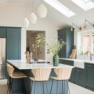 Blue Shaker kitchen with kitchen island with rattan bar stools and roof windows