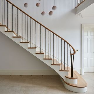 A wooden and white staircase with a pendant light
