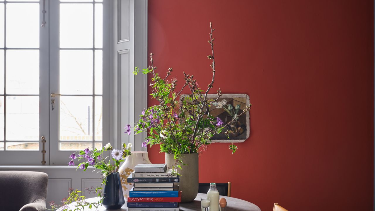 Farrow &amp; Ball Bamboozle No.304 in a large living room with a wide window, and a middle table with flowers and books on it