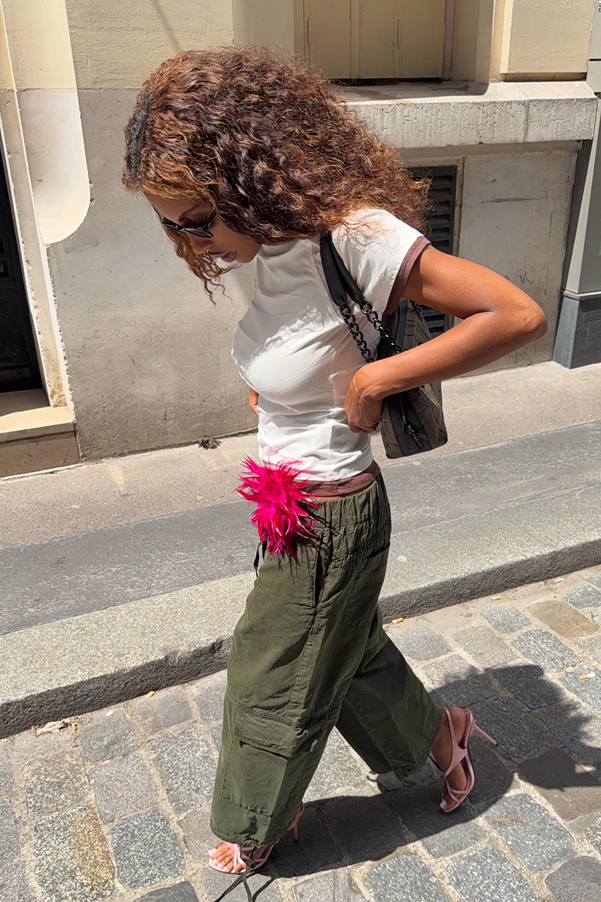 a woman wearing a white baby tee, green cargo pants, and pink high heel sandals