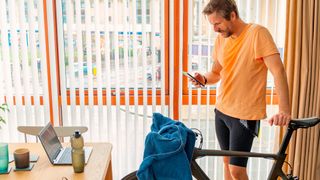 Man looking at phone standing next to turbo trainer
