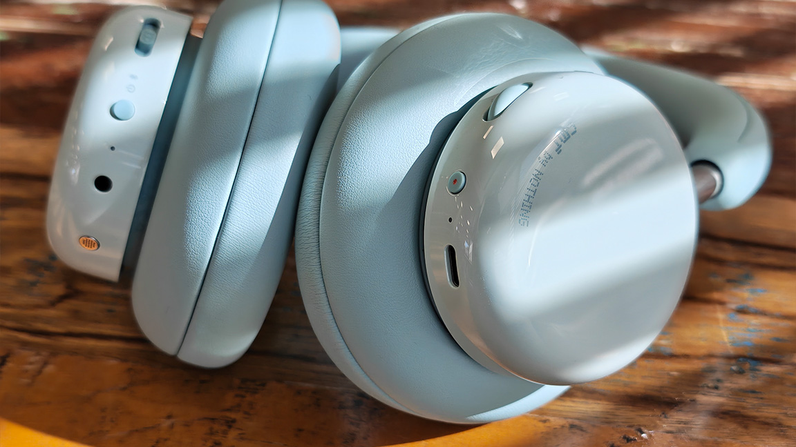 CMF Headphone Pro; a pair of light green headphones on a wooden table