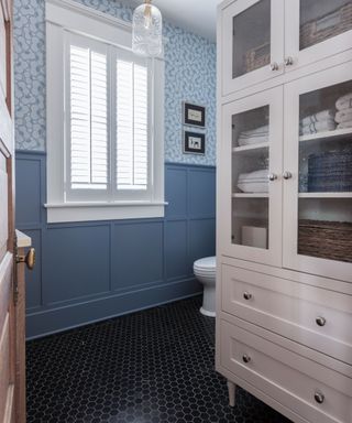 A blue bathroom with a white freestanding cabinet