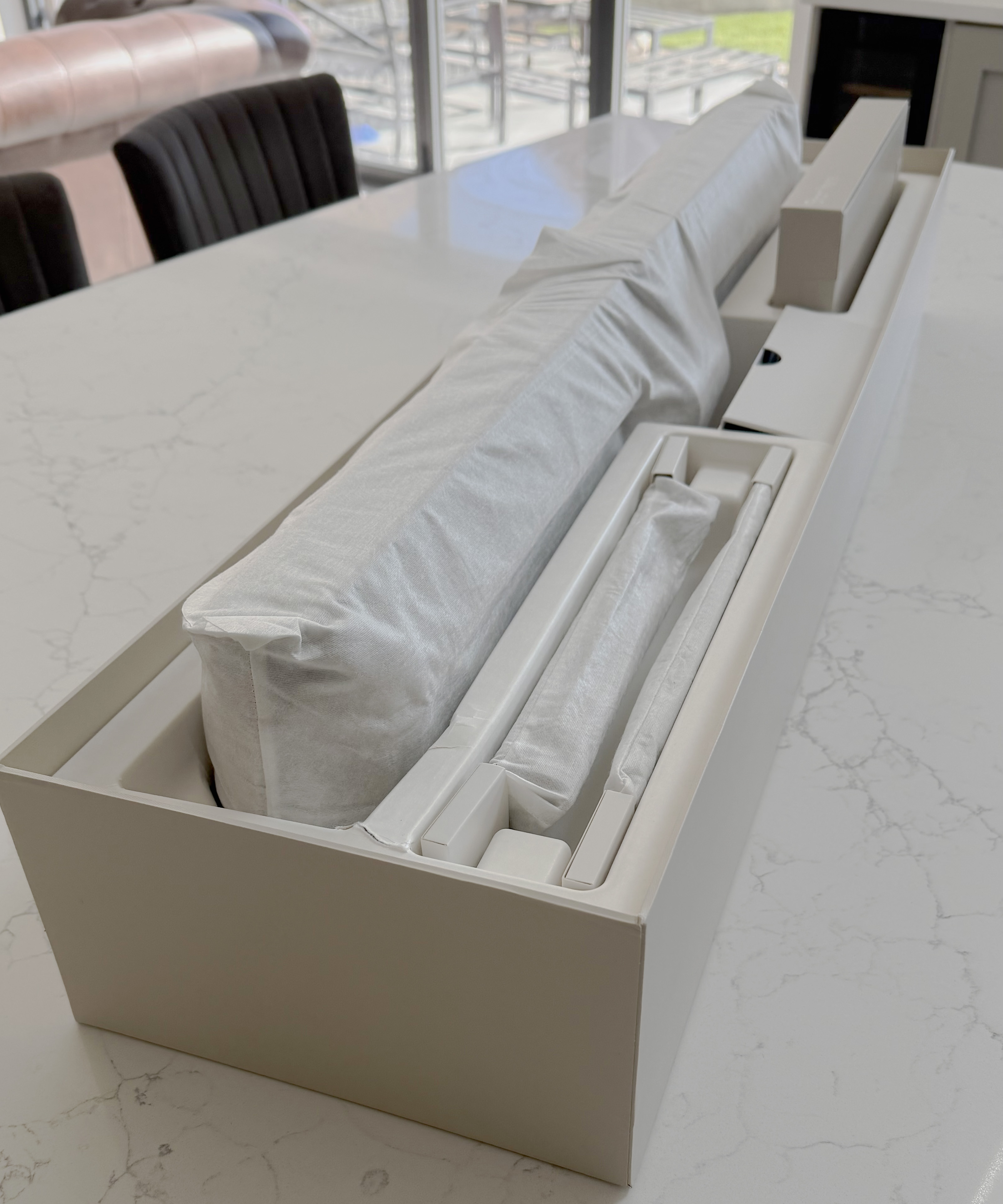 Open product box showing the Beosound Premiere soundbar wrapped in protective material alongside packaging inserts