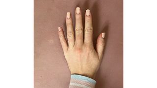 A close-up of Digital Beauty Editor, Fiona McKim's milky pink square nails/ in front of a terracotta-pink background