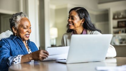 An adult daughter is helping her senior mother look over bills or finances at home.