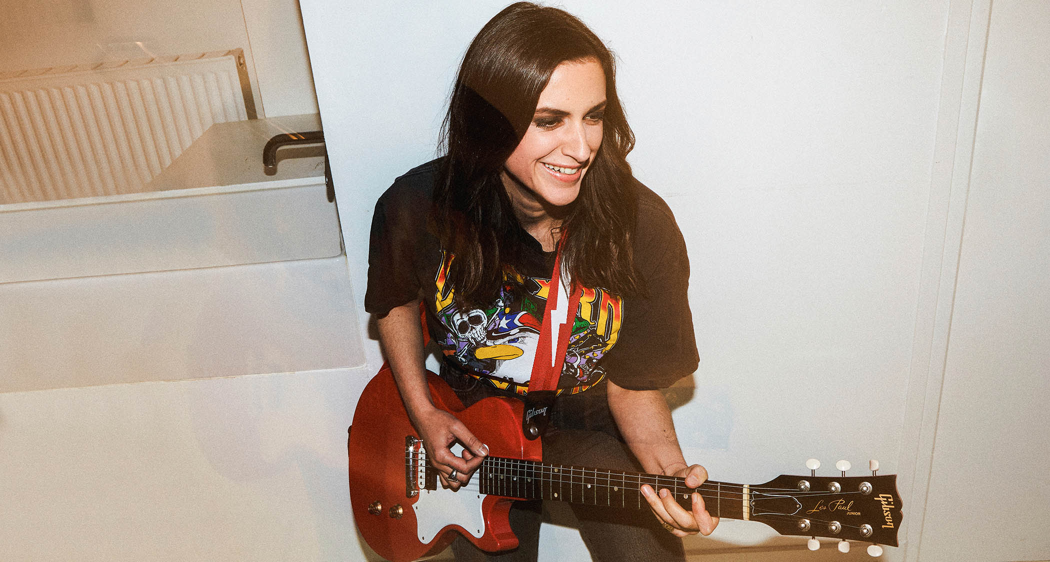 Laura Cox strikes an action pose with a Gibson electric guitar