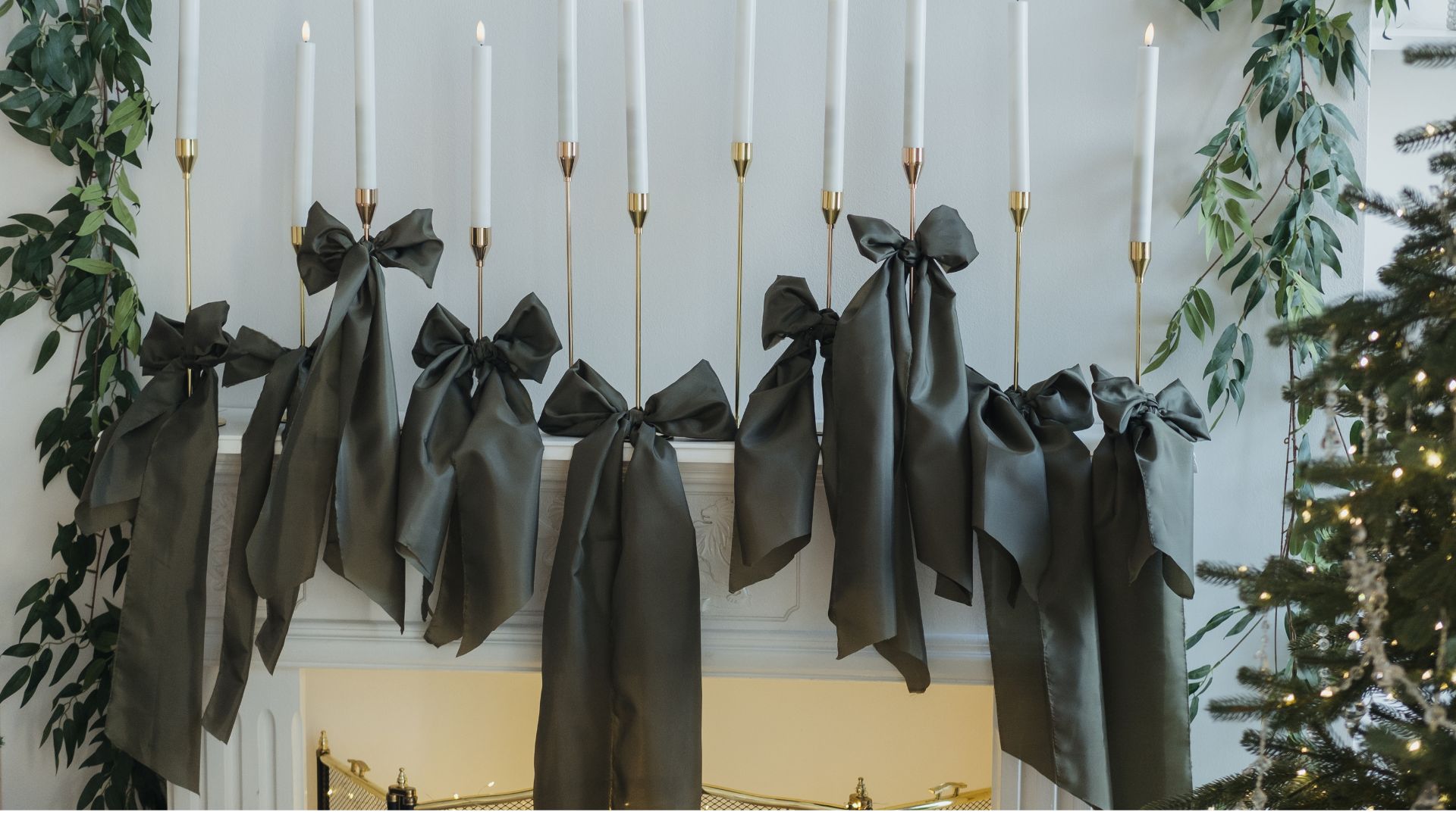 picture of tall candles with bows draping over fireplace on mantel