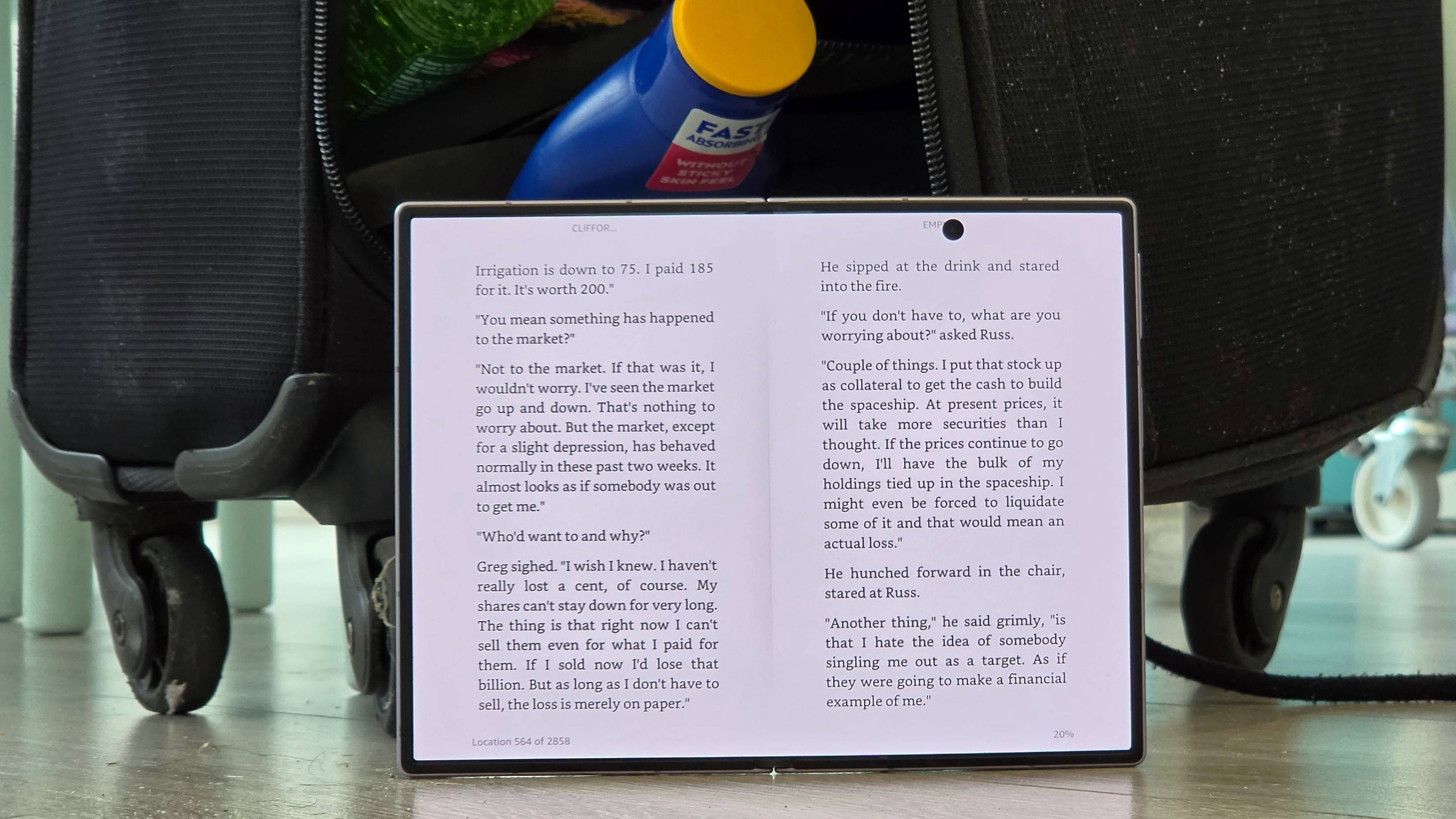 The Samsung Galaxy Z Fold 8 in the Kindle app, next to a suitcase with the contents spilling out.