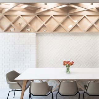 wooden lattice work on wall with rooflights overhead overlooking simple dining table