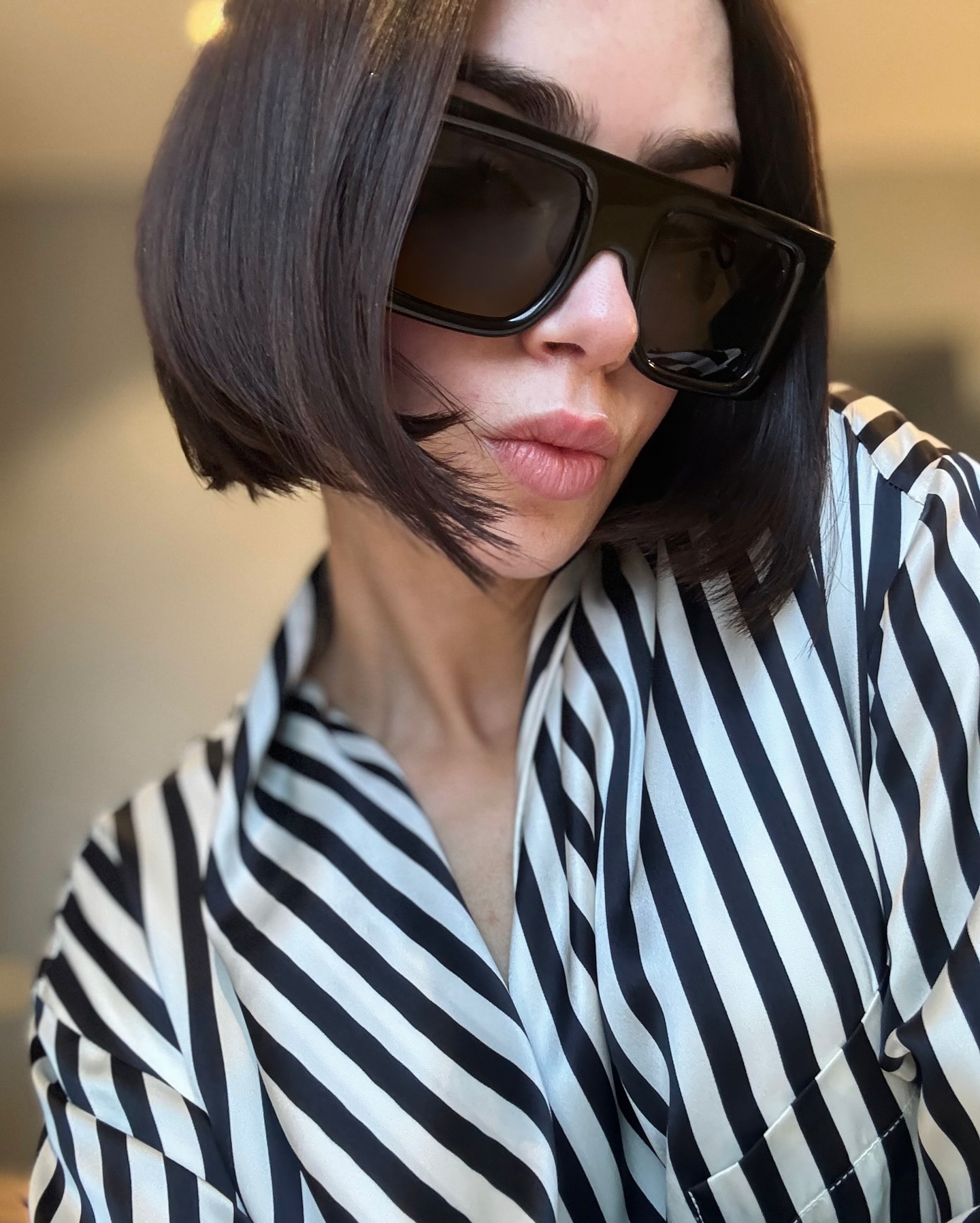 Lily Collins with a blunt bob hairstyle wearing oversized sunglasses