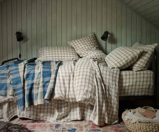 White Stripe linen bedding on a bed against a green wall.