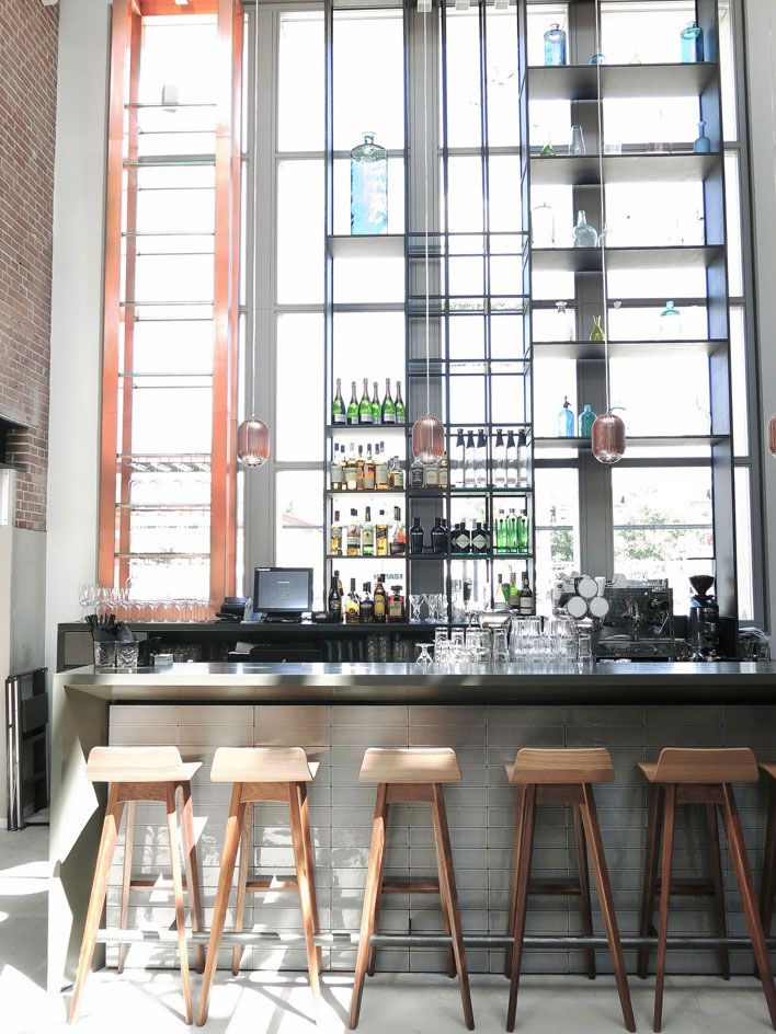 Hotel De Hallen Bars&#039; wooden bar stools glass shelving &amp; large windows