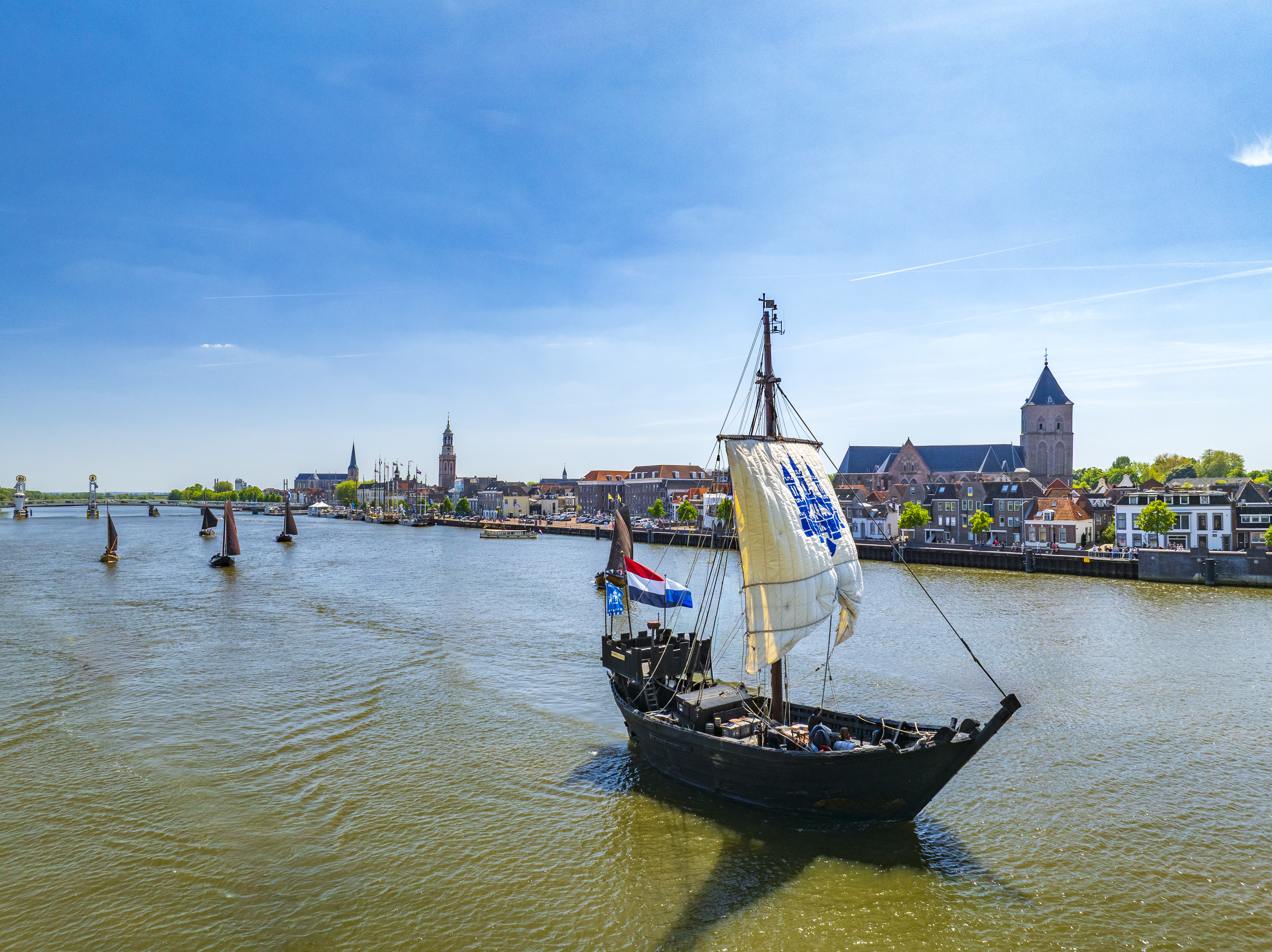 A photo of a historic replica of a medieval cog, the Kamper Kogge, sailing down IJsse river in the Netherlands.