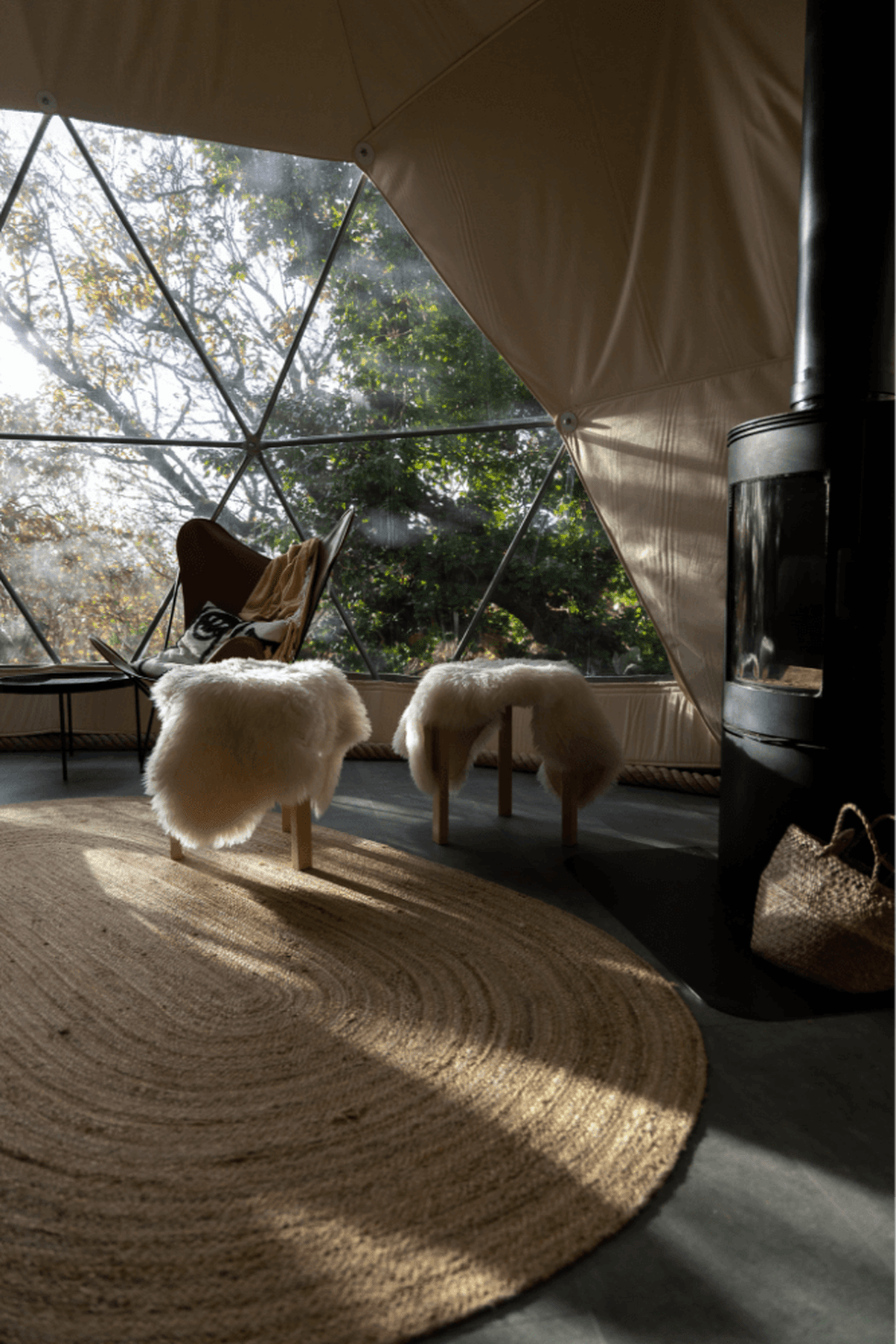 A sun-filled glamping dome is decorated with modern rustic decor.