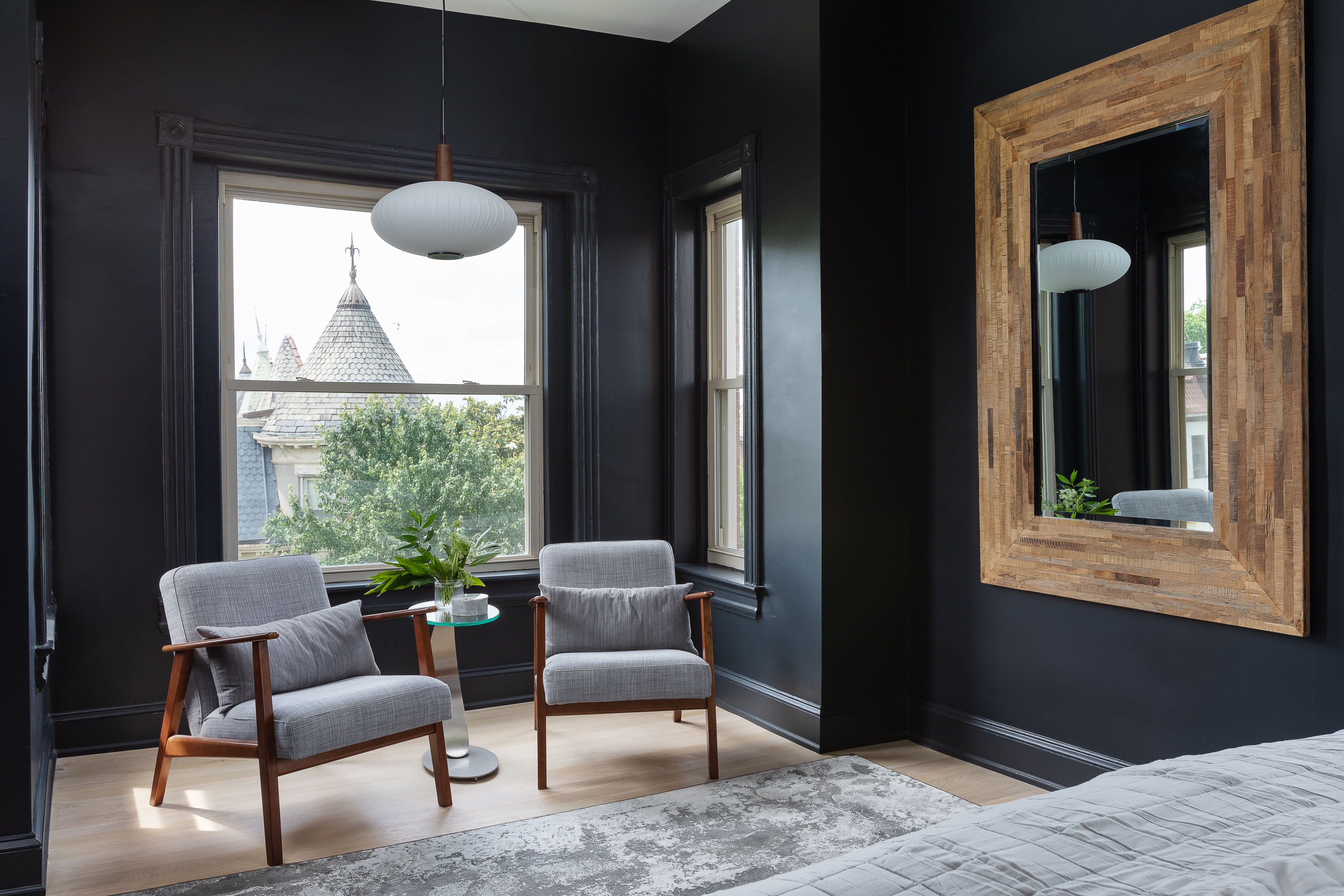 A bedroom with dark navy walls and mid century style furniture