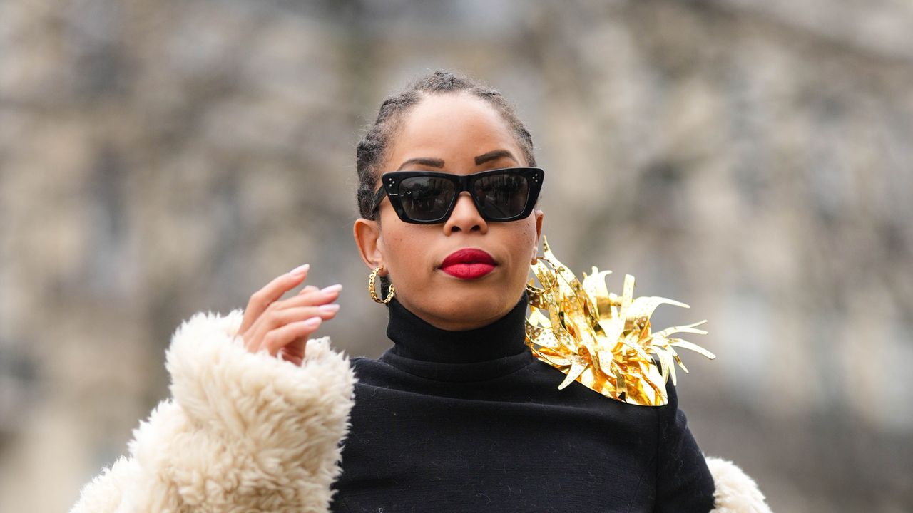 best liquid lipsticks - Ellie Delphine wears black sunglasses, gold earrings, a black turtleneck pullover, a white latte oversized sheep fur long coat, gray denim wide legs pants, outside Stephane Rolland, during Paris Fashion Week - Haute Couture Spring Summer, on January 24, 2023 in Paris, France