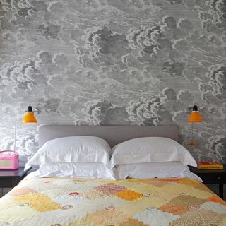 Grey bedroom with cloud wallpaper and orange bedside lamps
