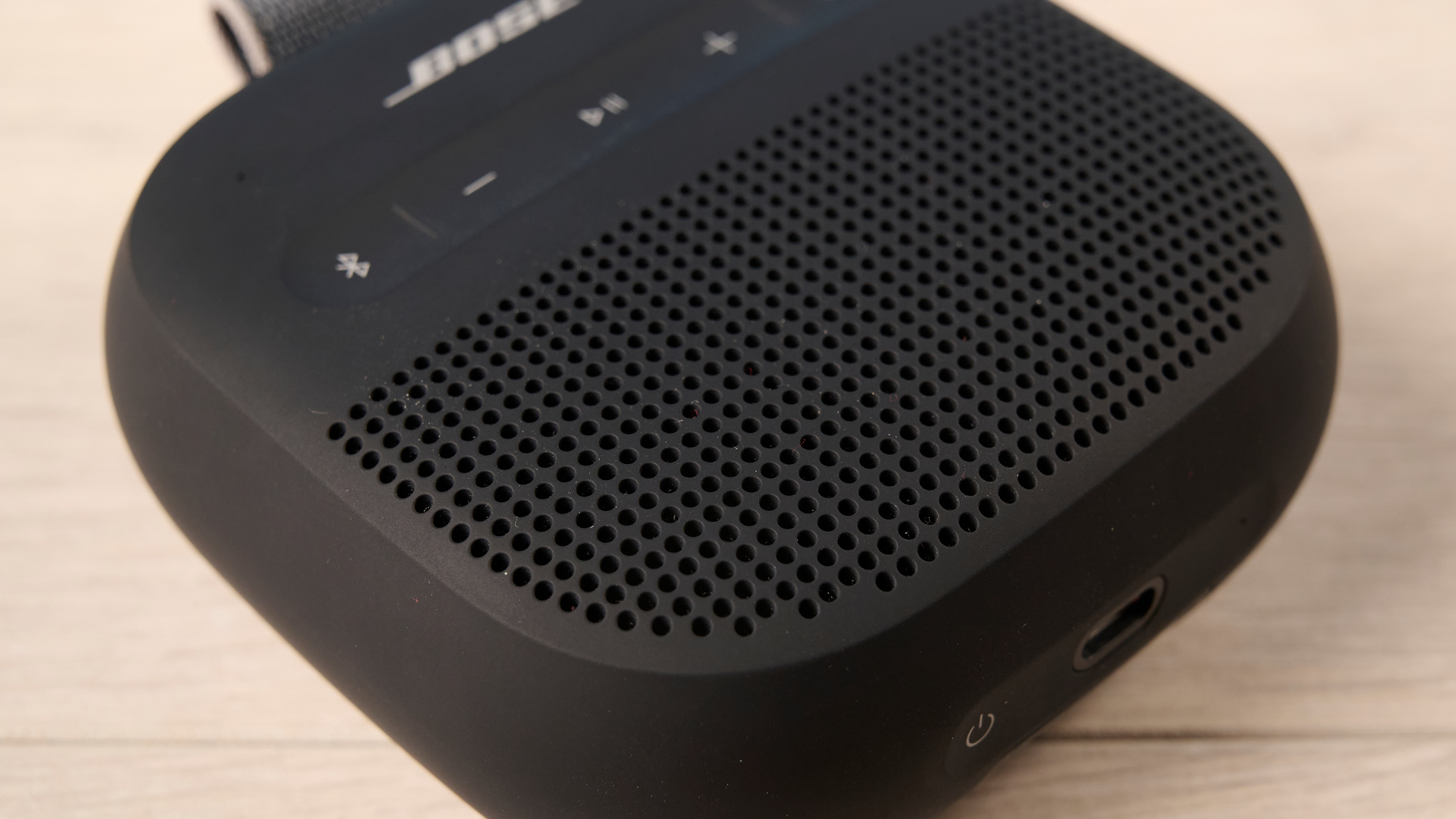 Bose SoundLink Micro 2 in black photographed in front of a blue background