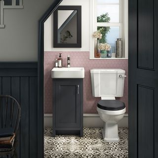 An under stairs toilet with pink and white walls and black paintwork