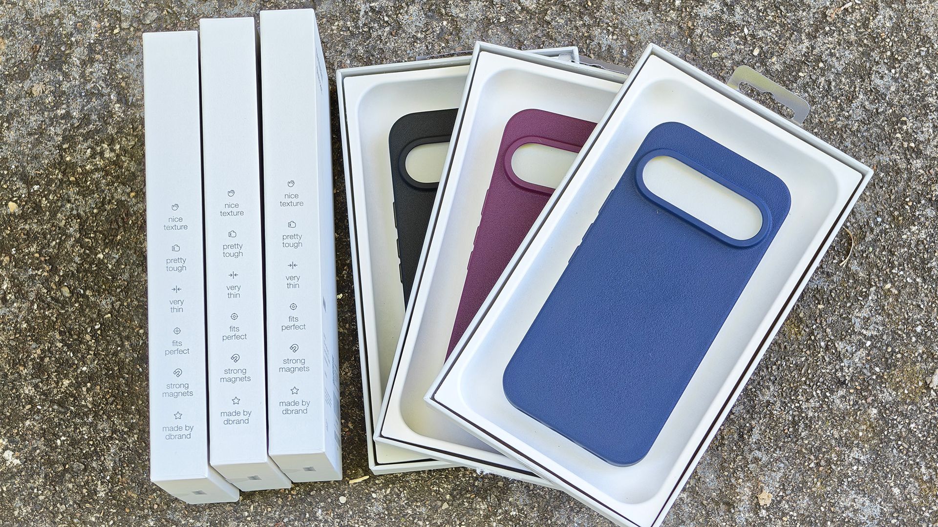 Three different colors of Dbrand MNML case and the retail boxes