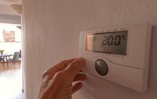 hand adjusting wall-mounted thermostat