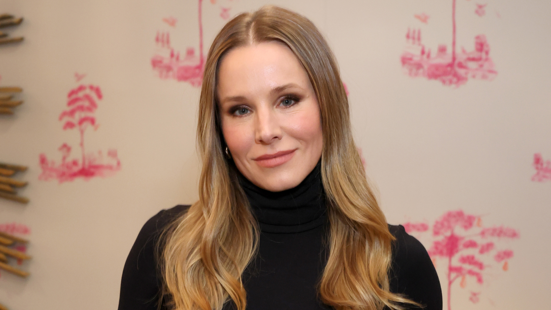 Kristen Bell wearing a black turtle neck and smiling at the camera