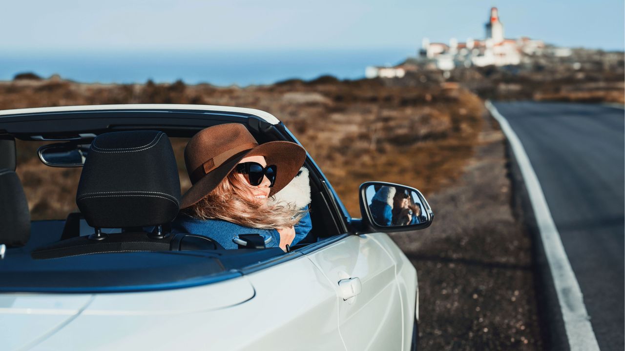 A woman driving a convertible car