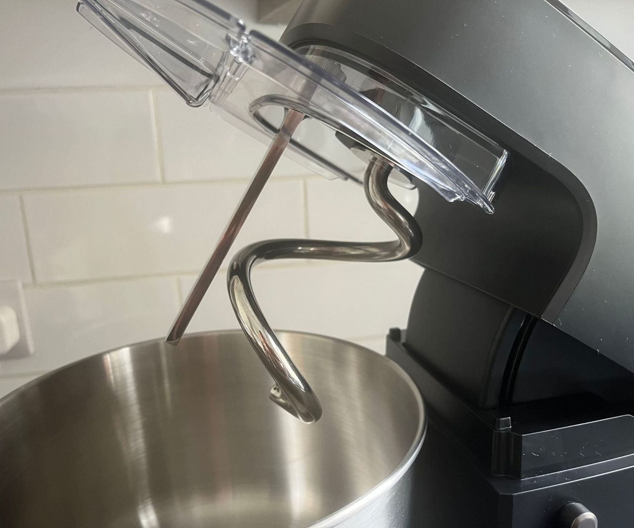 A close up of the dough hook and breaker bar on a black stand mixer
