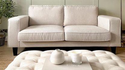 living room with white sofa and pouffe with green wall panelling