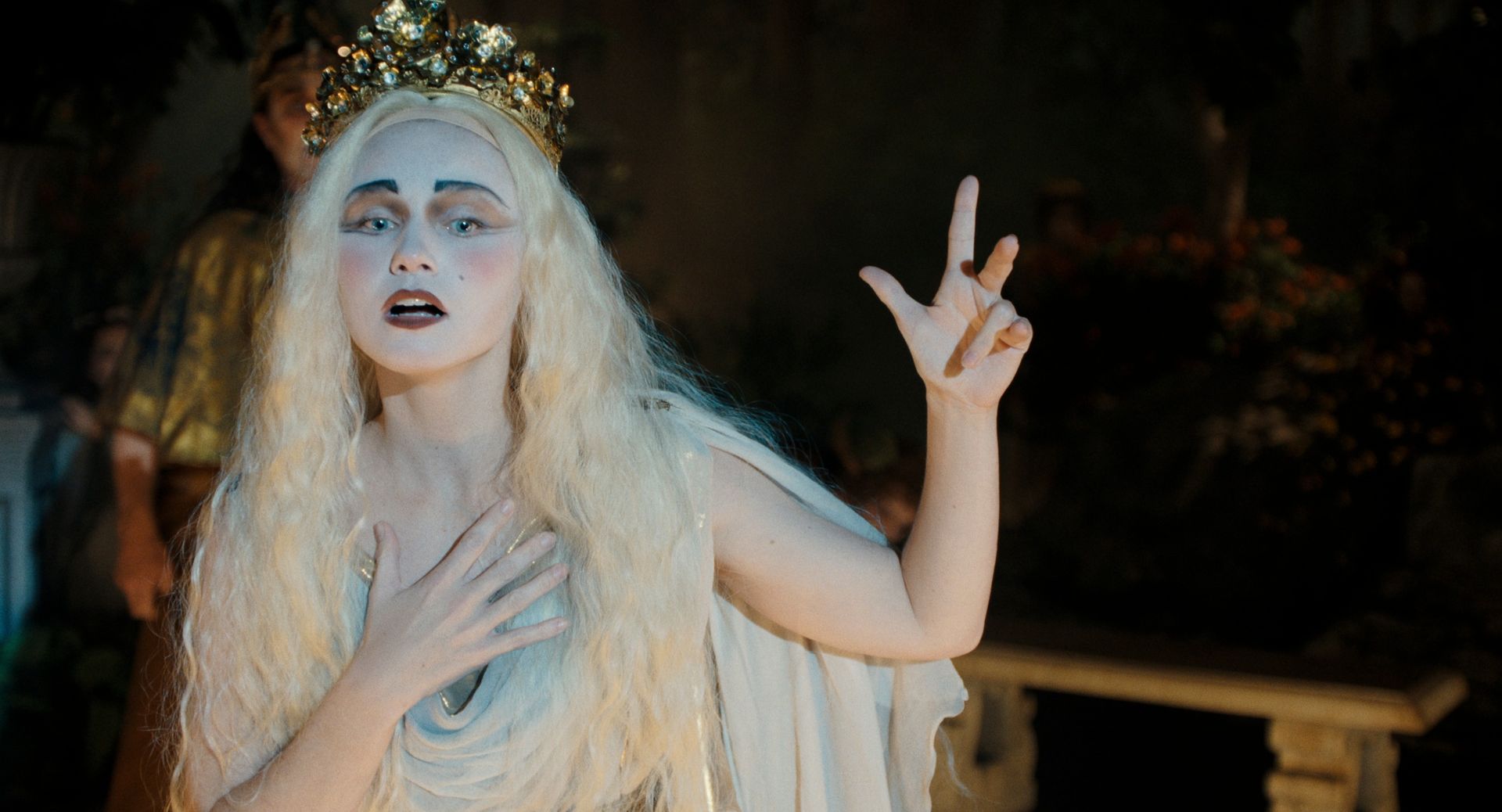 jessica barden as actress nance o'neil wearing white makeup and a blonde wig singing on stage in monster the lizzie borden story