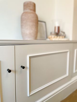 A close up of a cream TV stand with molding detail