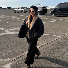 aimee song wearing a fur trim coat while traveling