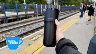 Ember TravelMug 2+ in the hand at a station platform in the UK