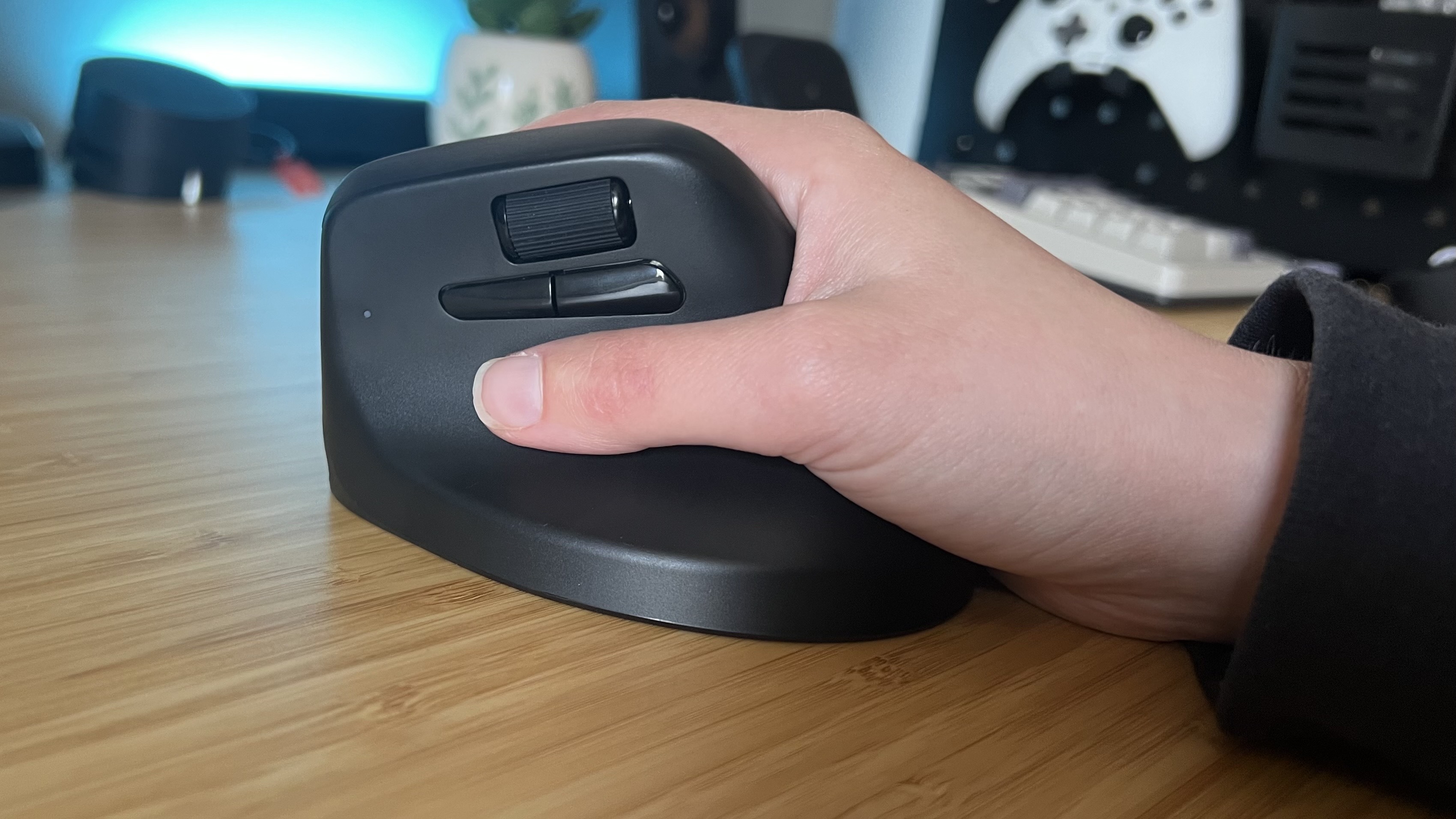 Hand holding Keychron M5 vertical mouse in a gaming setup