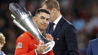 Cristiano Ronaldo, wearing red of Portugal, holds the Nations League trophy.